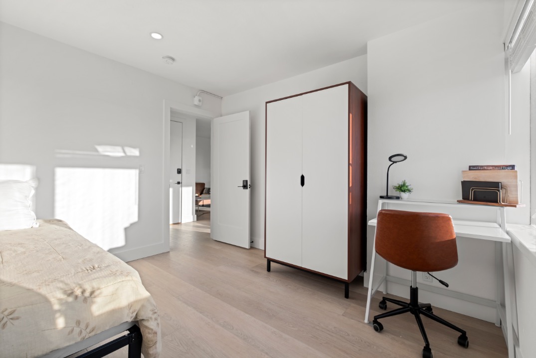 Bright and modern bedroom with sleek design, featuring a cozy bed, stylish wardrobe, and a functional desk area with natural light.