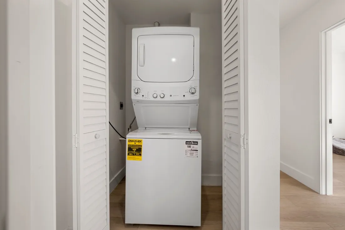 Compact laundry area with modern stacked washer and dryer.