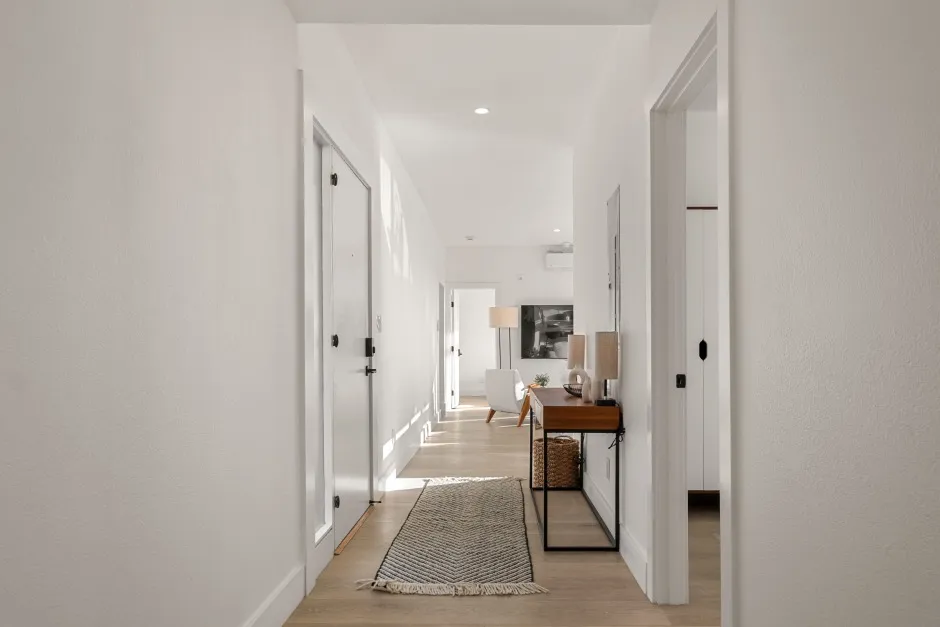 Bright and inviting hallway leading to a cozy living room, featuring elegant decor and natural wooden flooring.