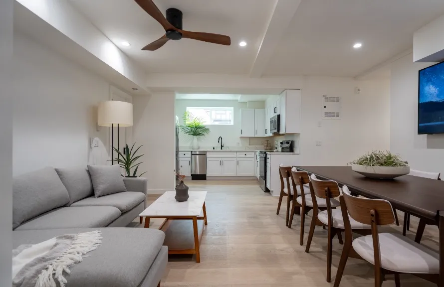 Modern open-concept living space featuring cozy sofa, elegant dining area, and sleek kitchen with bright lighting and contemporary decor.