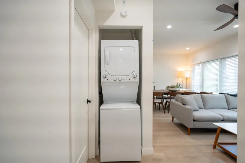 Modern apartment interior with a cozy living room, dining area, and in-unit washer-dryer combo.