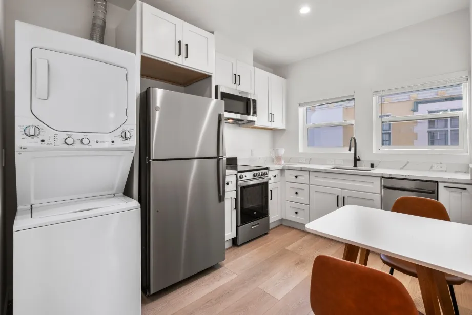 Modern kitchen with sleek stainless steel appliances, integrated laundry, and stylish dining space.