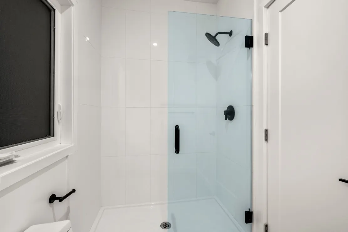 Elegant bathroom with sleek glass shower door and modern matte black fixtures, offering a stylish and contemporary design.
