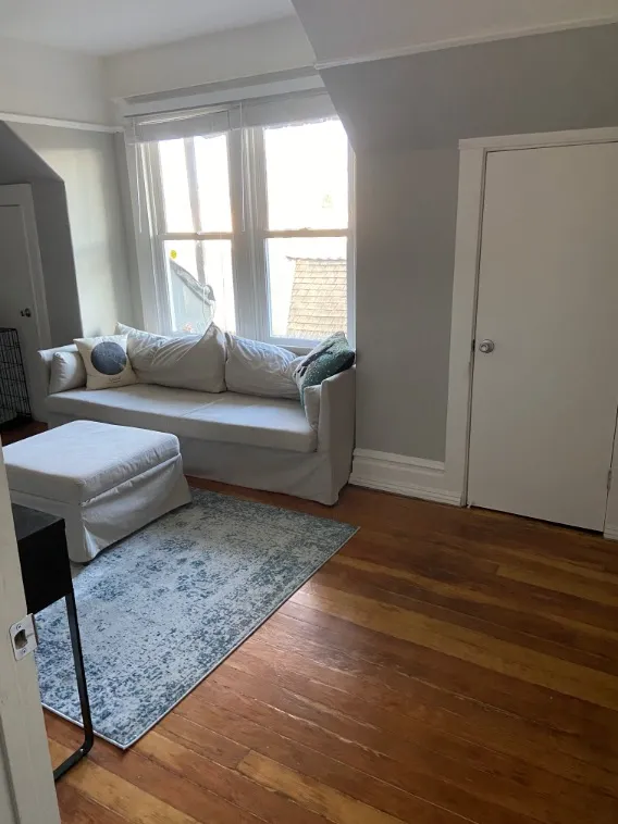 Charming living area with large windows, cozy white sofa, and elegant hardwood floors.