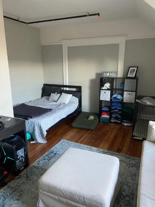 Cozy and stylish bedroom with modern furnishings, showcasing a comfortable bed, neat shelving unit, and chic decor on hardwood floors.