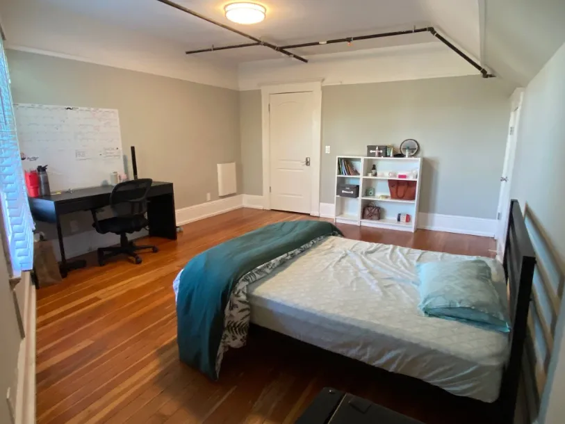 Cozy bedroom with a modern desk, comfortable bed, and hardwood floors, perfect for relaxation and productivity.
