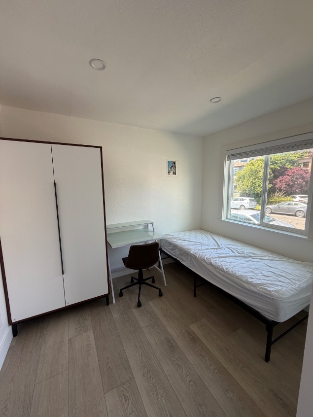 Charming bedroom with natural light, featuring a sleek wardrobe, cozy bed, and study desk, perfect for a restful and productive space.