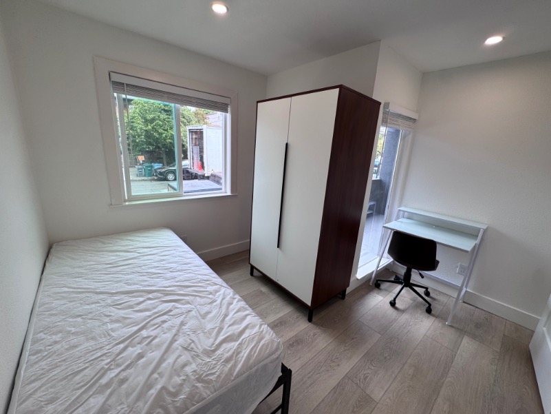 Bright and modern bedroom featuring a cozy single bed, sleek wardrobe, and a convenient study desk with chair by a large window.