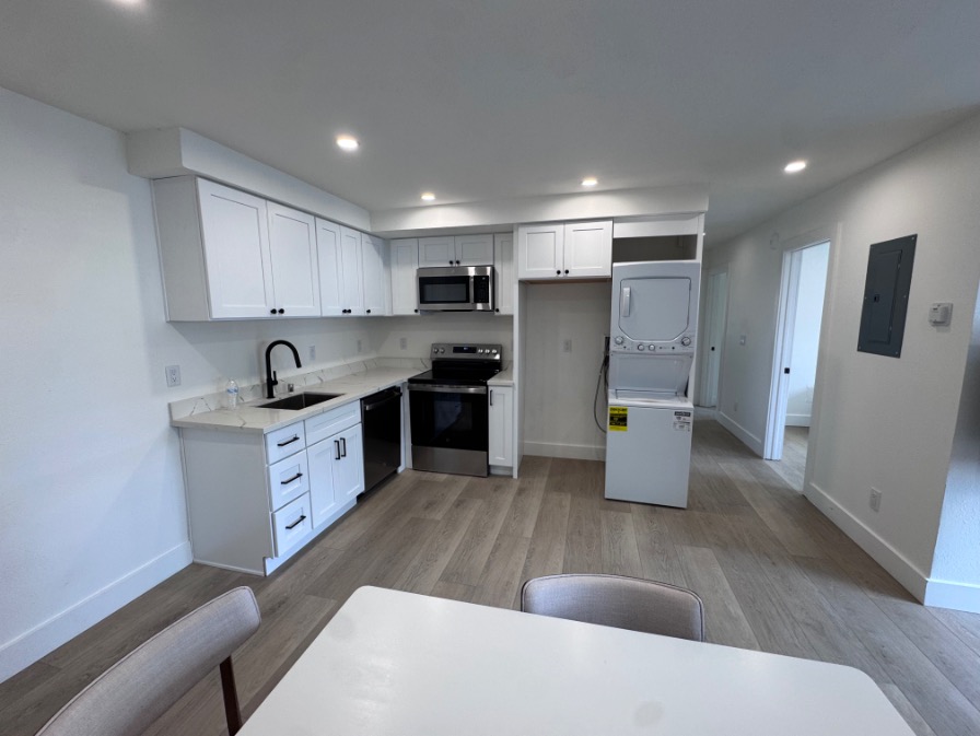 Modern kitchen with sleek white cabinetry, stainless steel appliances, and in-unit washer and dryer, perfect for stylish urban living.