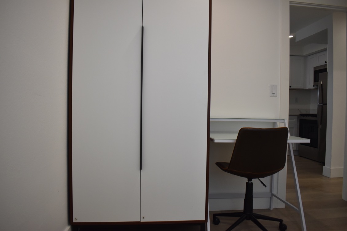 Sleek modern apartment corner with spacious wardrobe, compact desk, and comfortable chair.