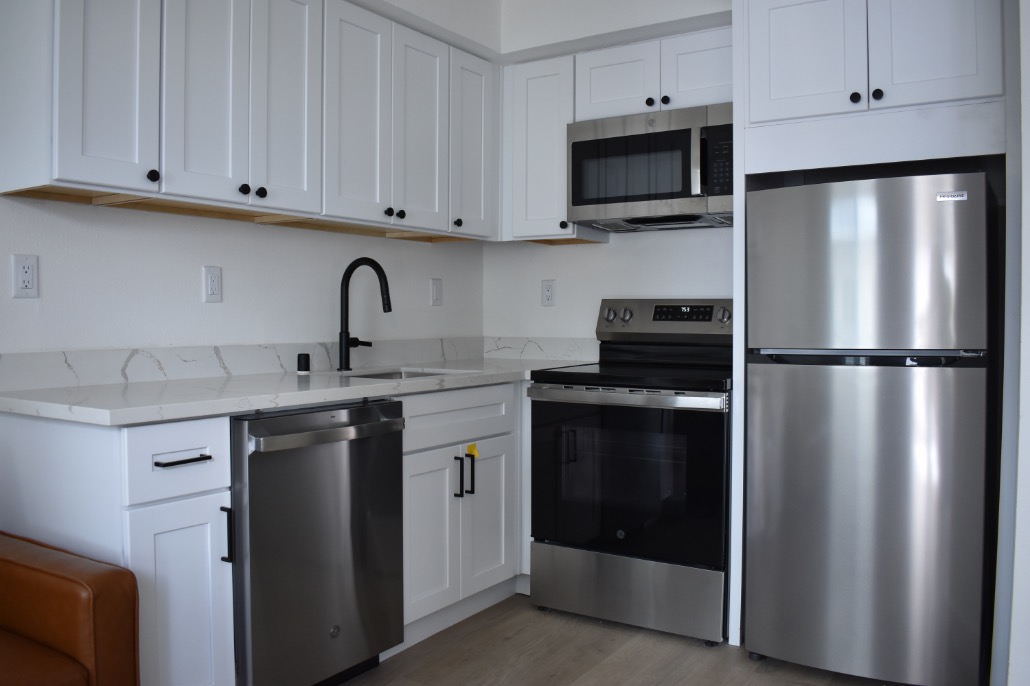 Modern kitchen with sleek stainless steel appliances, pristine white cabinetry, and elegant marble countertops.