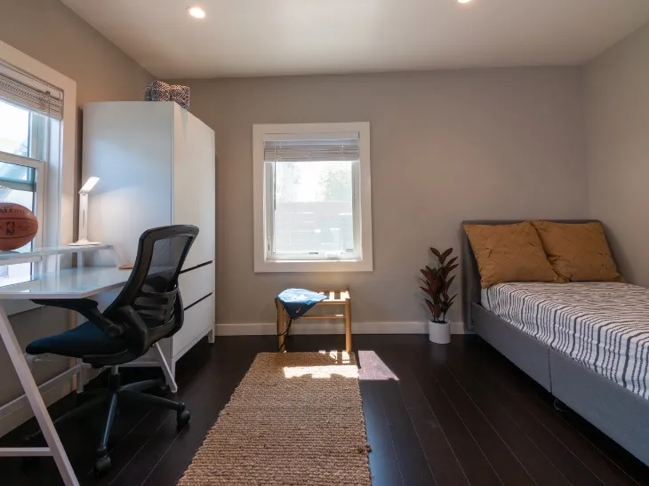 Inviting bedroom with modern desk, comfortable bed, and abundant natural light, perfect for productivity and relaxation.