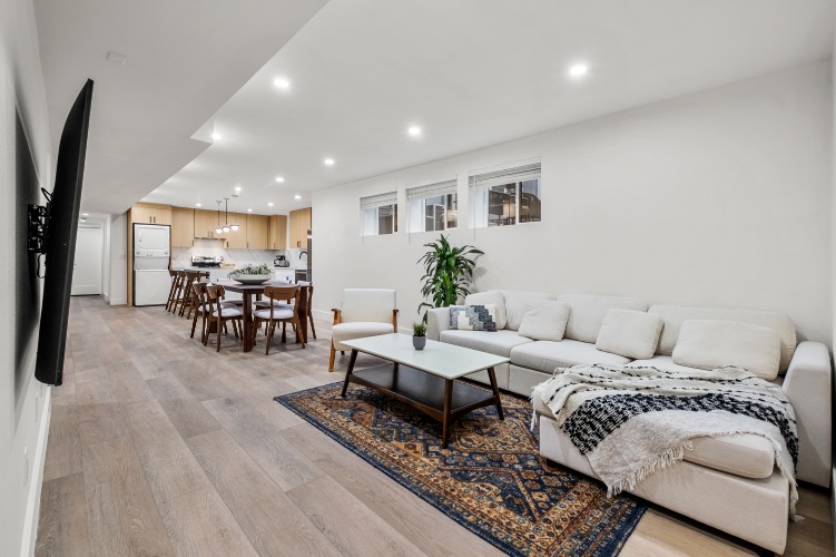Elegant open-concept living room with cozy white sofa, modern dining area, and sleek kitchen, perfect for stylish entertaining.