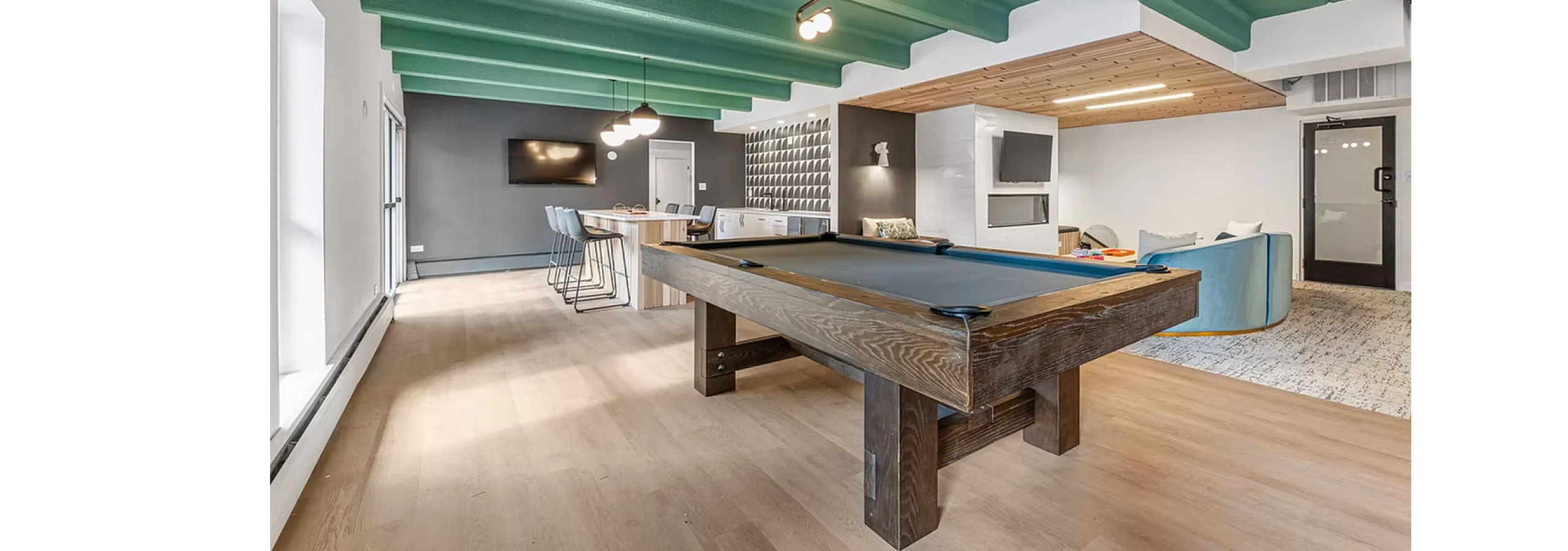 Modern recreational room with stylish pool table, vibrant green ceiling, and open lounge area perfect for entertaining.