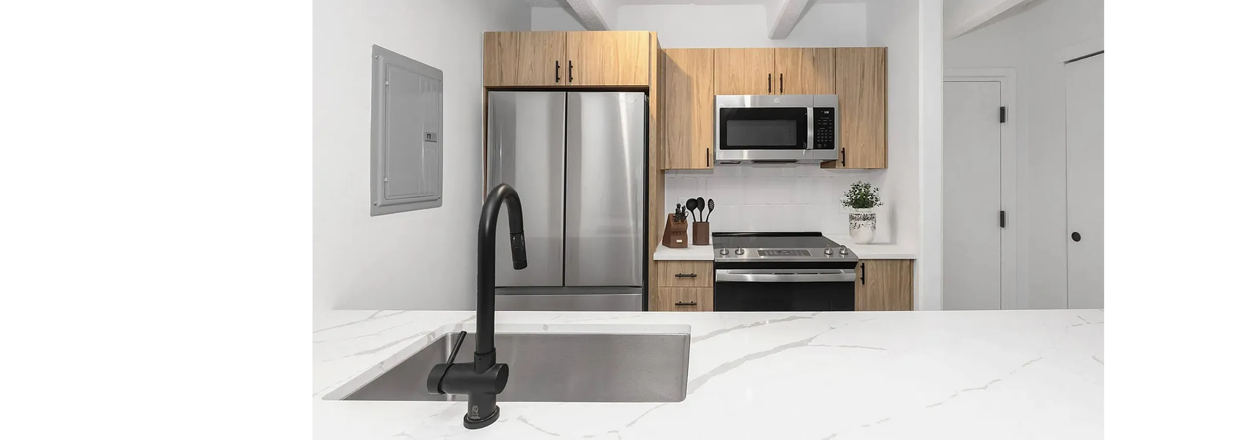 Modern kitchen featuring stainless steel appliances, a sleek marble countertop, and stylish wood cabinetry.