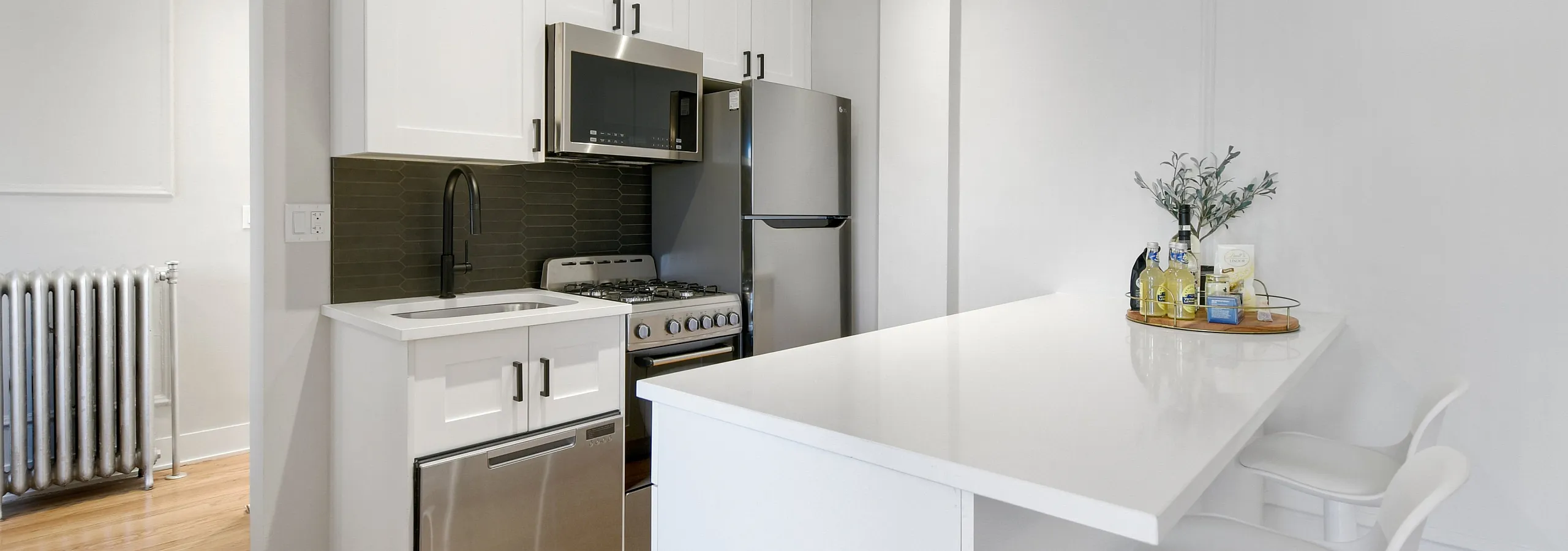 Bright modern kitchen with sleek white cabinetry, stainless steel appliances, and a stylish breakfast bar with cozy stools.