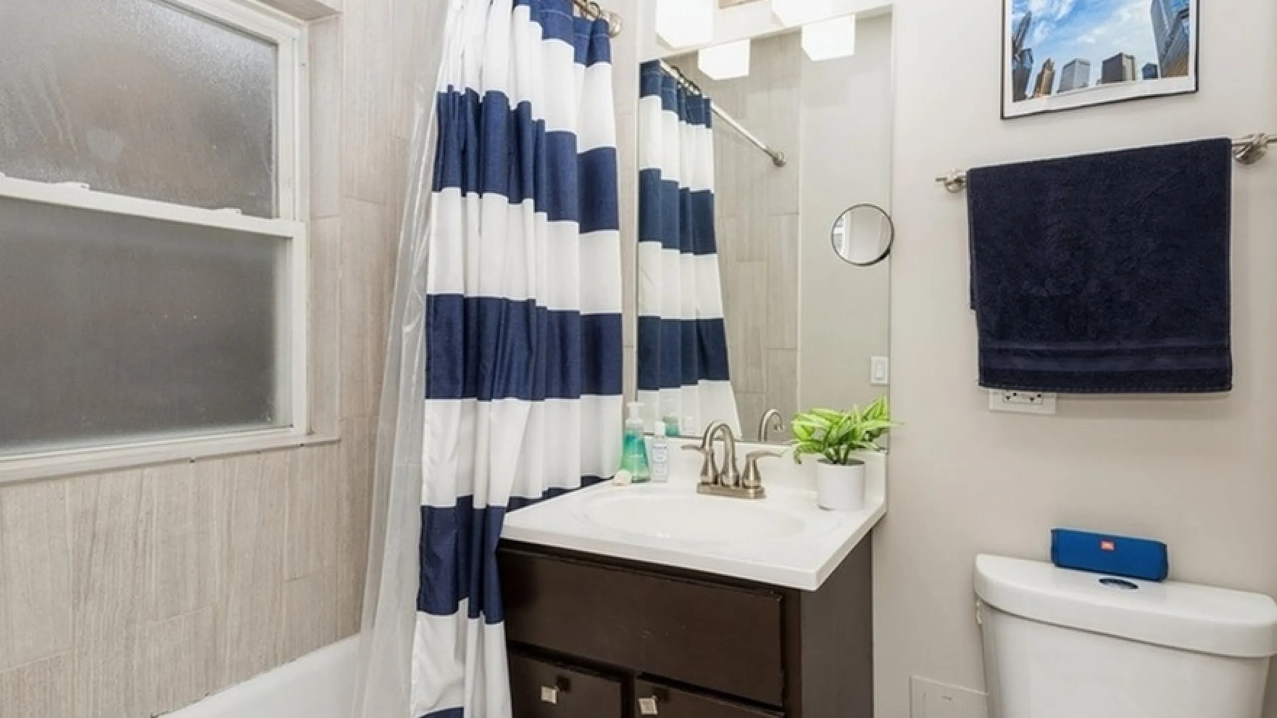 Elegant bathroom featuring a stylish vanity, modern fixtures, and a bold striped shower curtain, creating a refreshing and bright space.