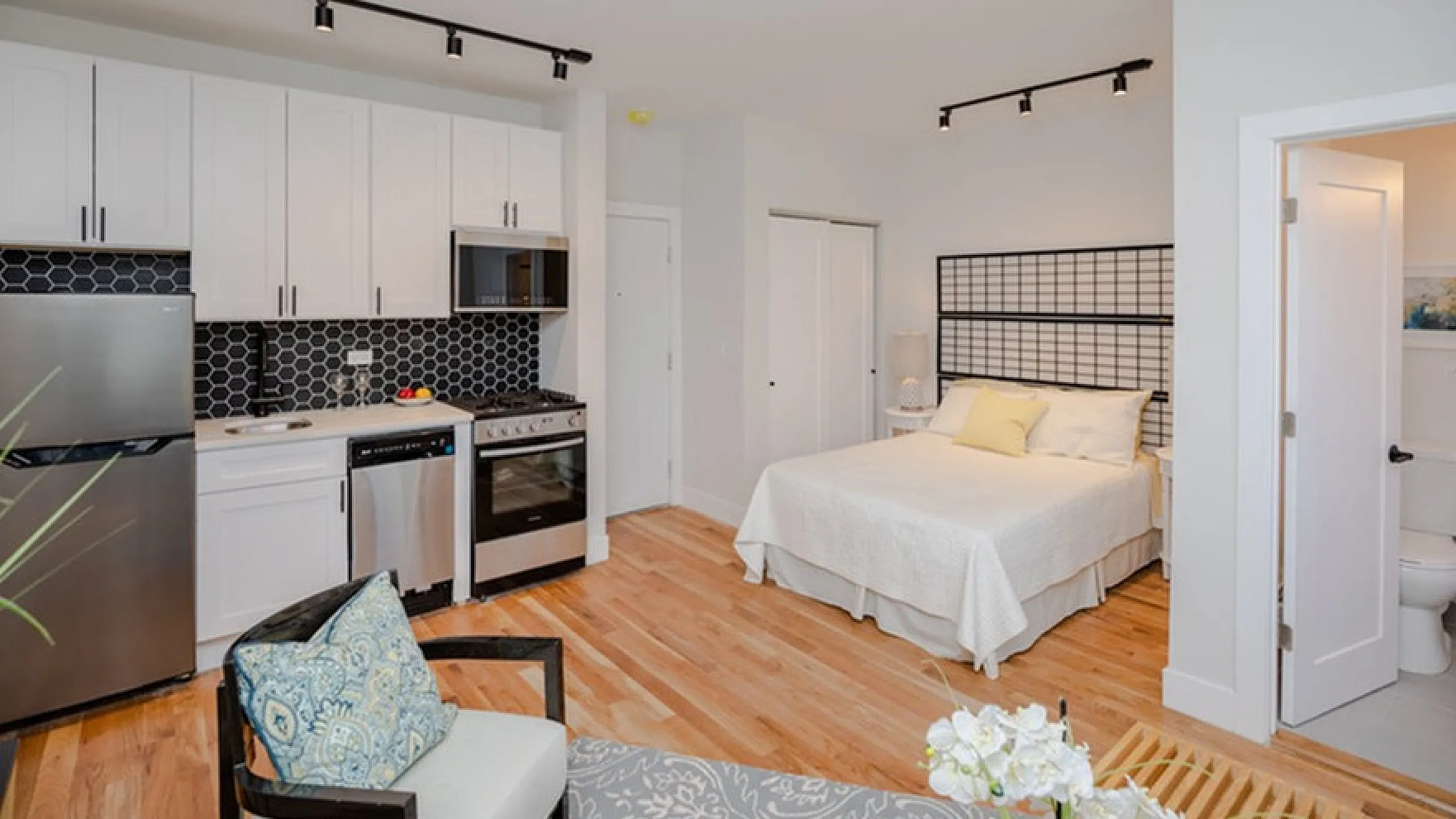 Chic studio apartment with open kitchen, elegant backsplash, and cozy sleeping area.