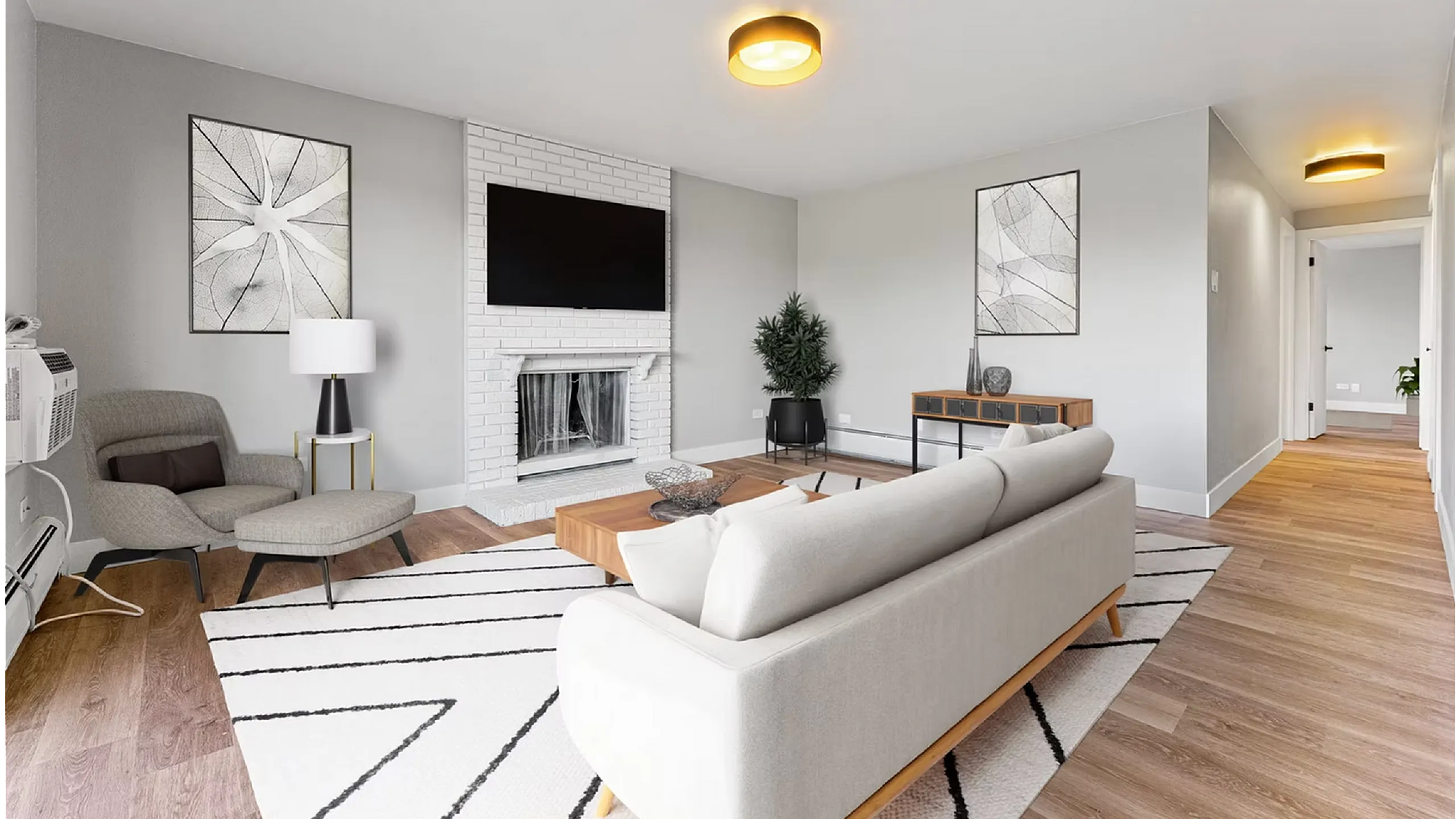 Sleek and modern living room featuring a cozy sofa, stylish armchair, and a flat-screen TV above a chic white brick fireplace.