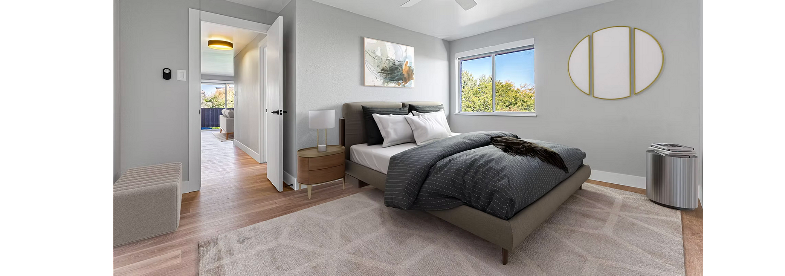 Bright and modern bedroom with cozy decor, large window view, stylish artwork, and elegant ceiling fan.