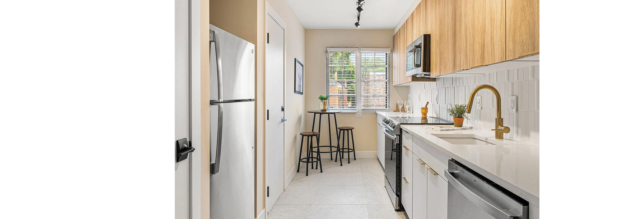 Chic modern kitchen with sleek cabinetry, stainless steel appliances, and elegant gold faucet, featuring a cozy dining nook with natural light.