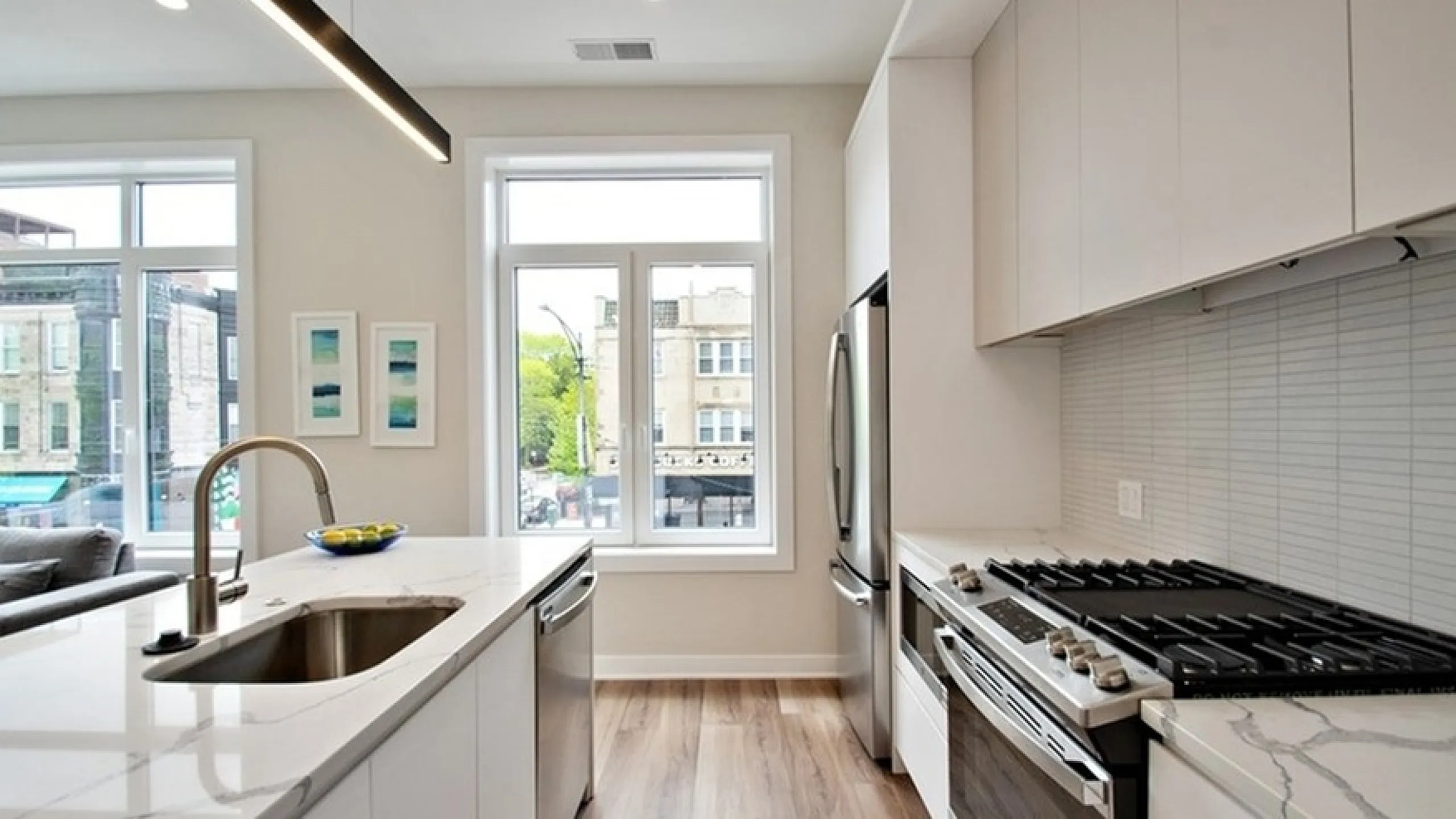 Bright, modern kitchen with sleek countertops, stainless steel appliances, and a sunlit view from large windows.