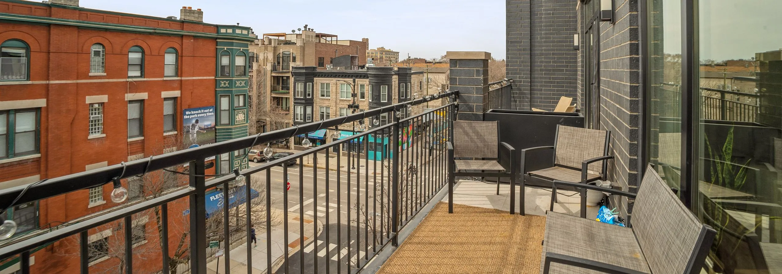 Charming balcony with modern seating offering a vibrant city view, perfect for relaxation and entertaining.