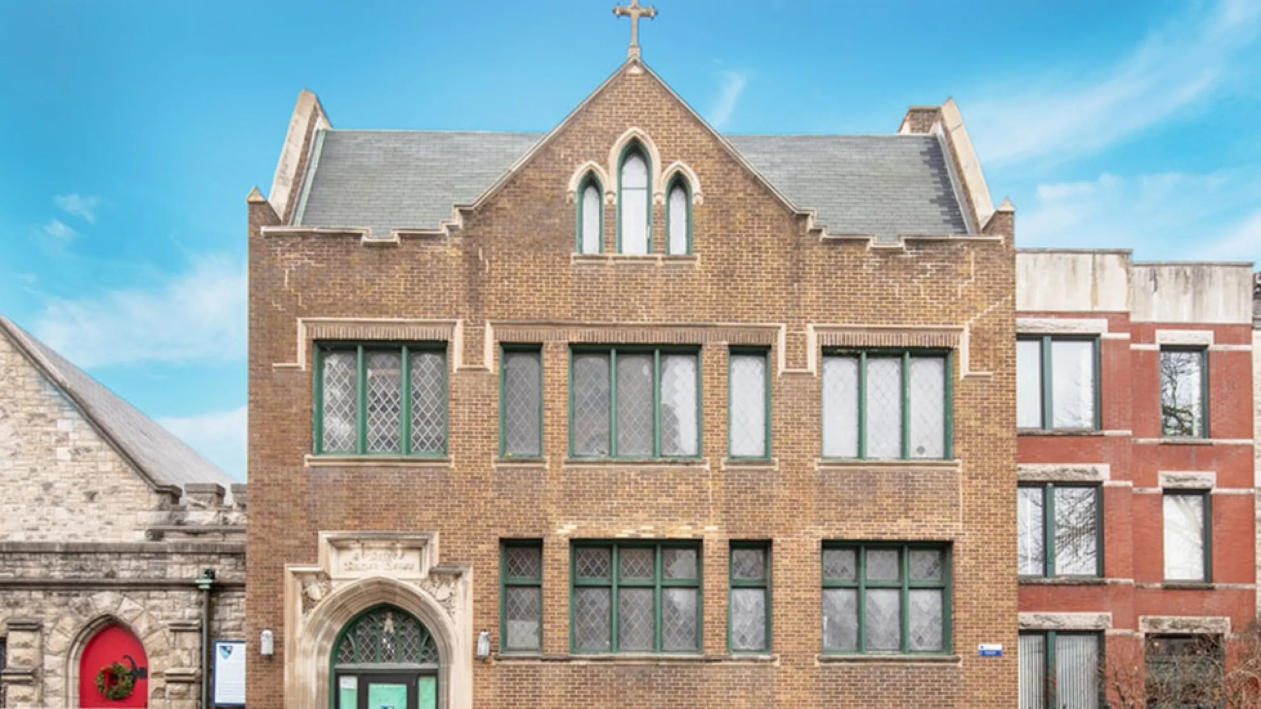 Charming historic building with Gothic architecture, featuring arched windows and intricate stonework under a vibrant blue sky.