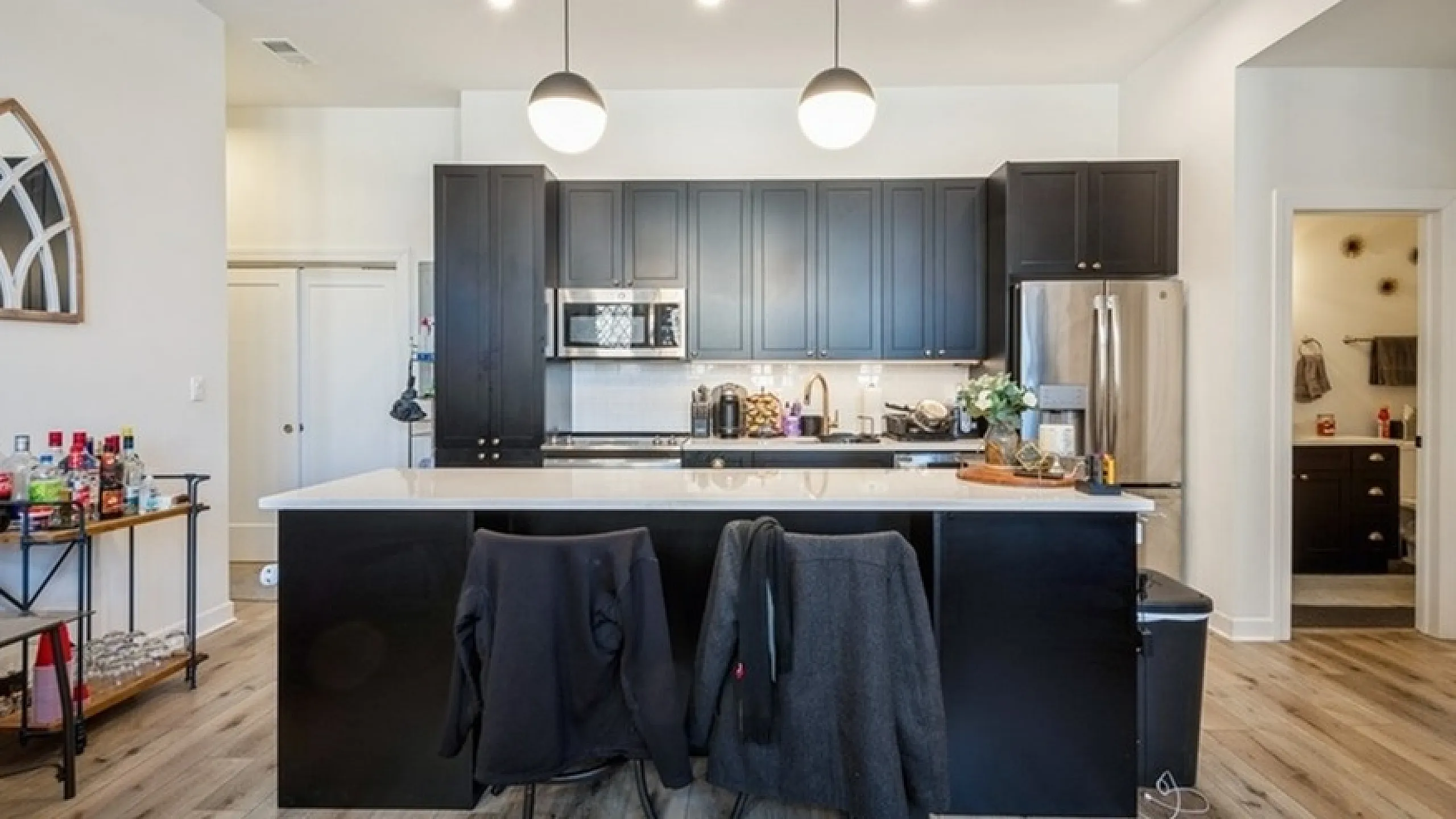 Modern kitchen with sleek black cabinets, stainless steel appliances, and elegant pendant lighting over an island counter.