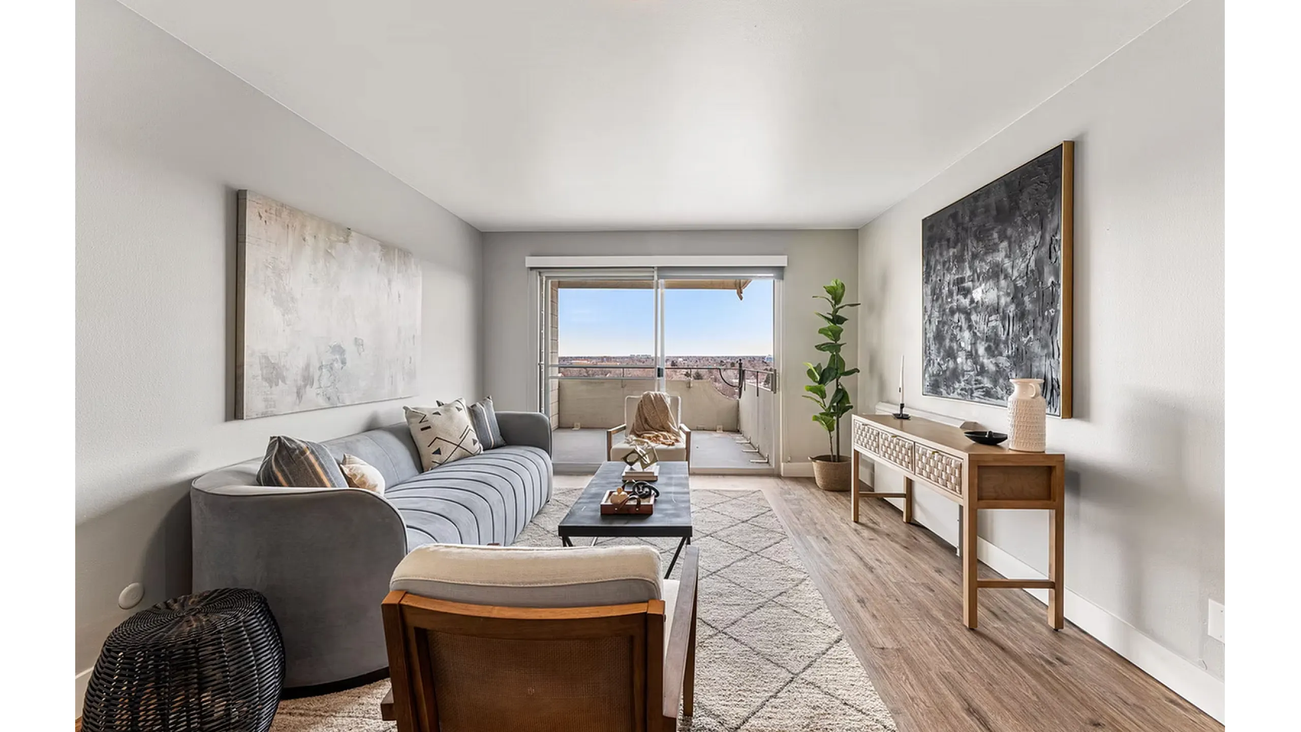 Elegant living room with modern gray sofa, stylish decor, and large window offering scenic balcony views.