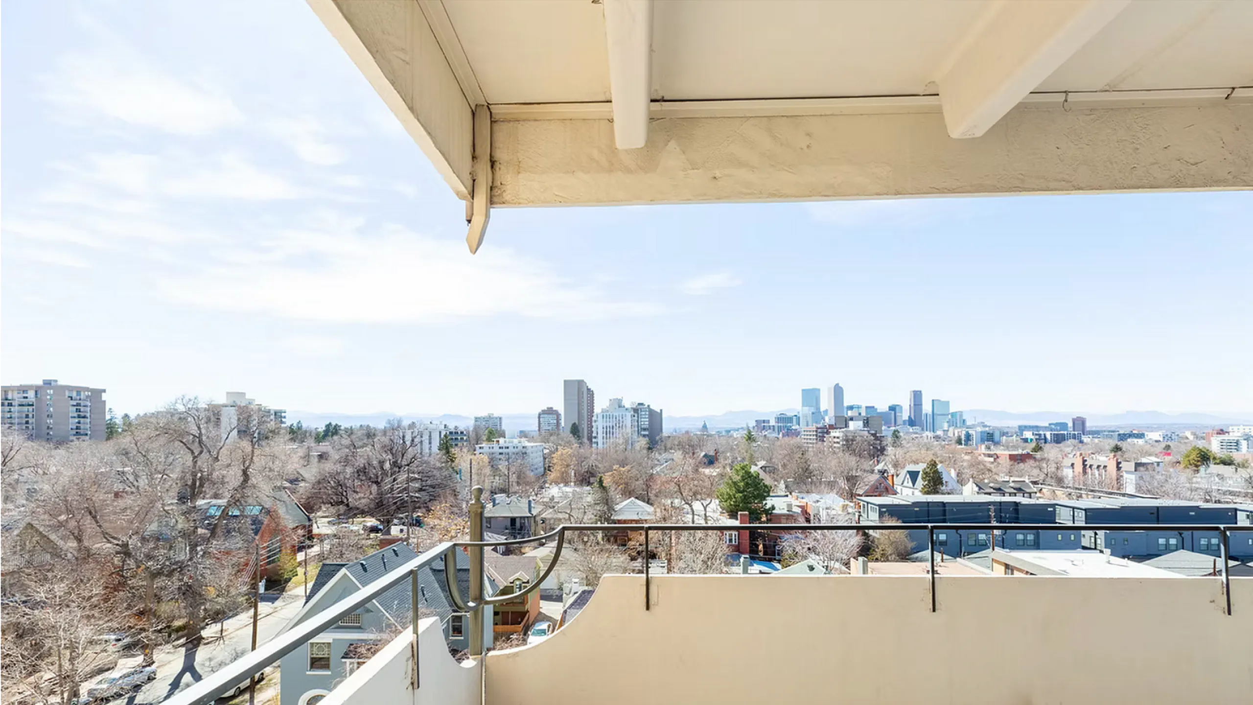 Breathtaking urban skyline view from a stylish balcony, showcasing a vibrant cityscape under clear blue skies.