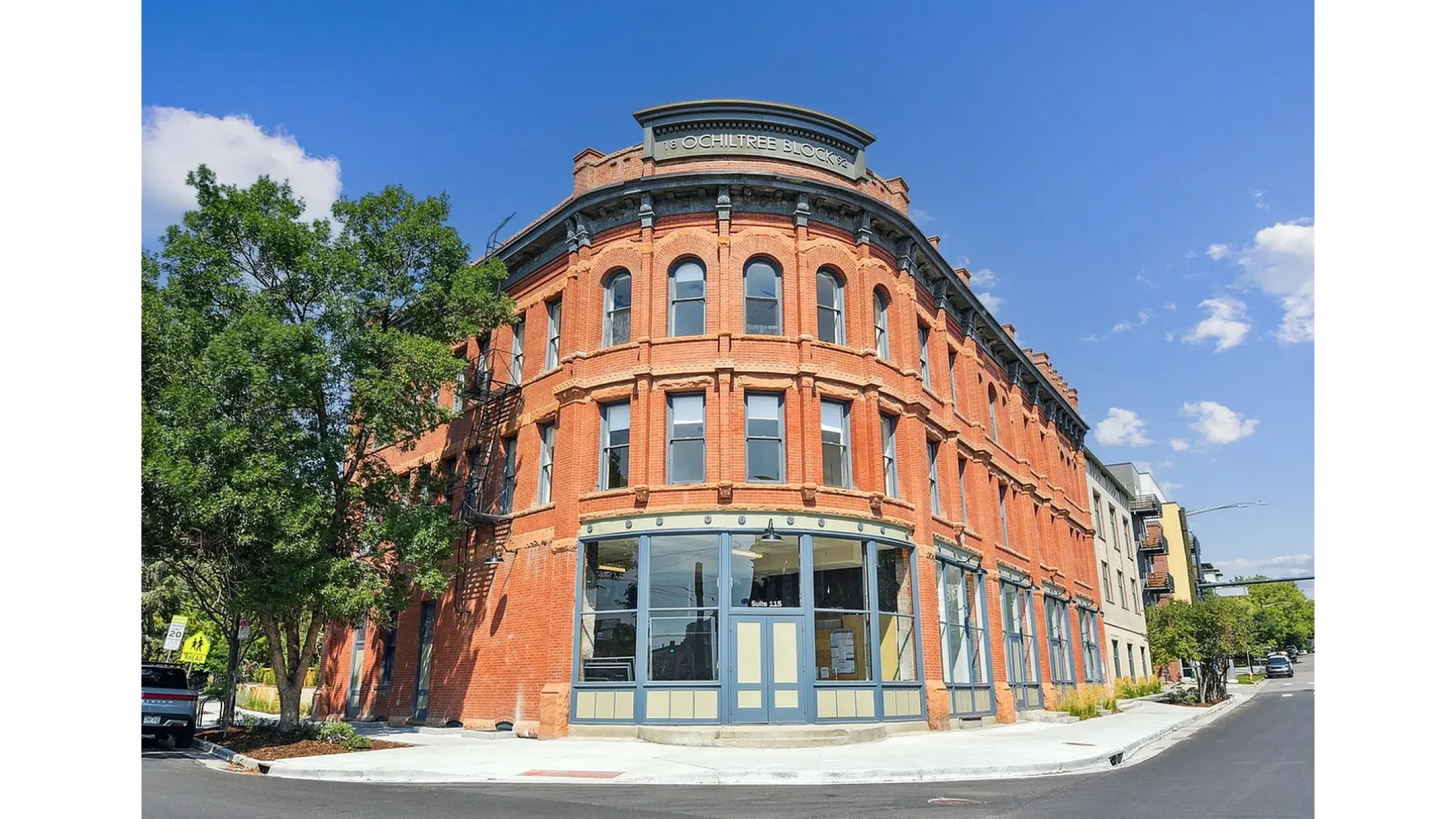 Charming historic red-brick building with large arched windows under a clear blue sky, perfect for urban living.