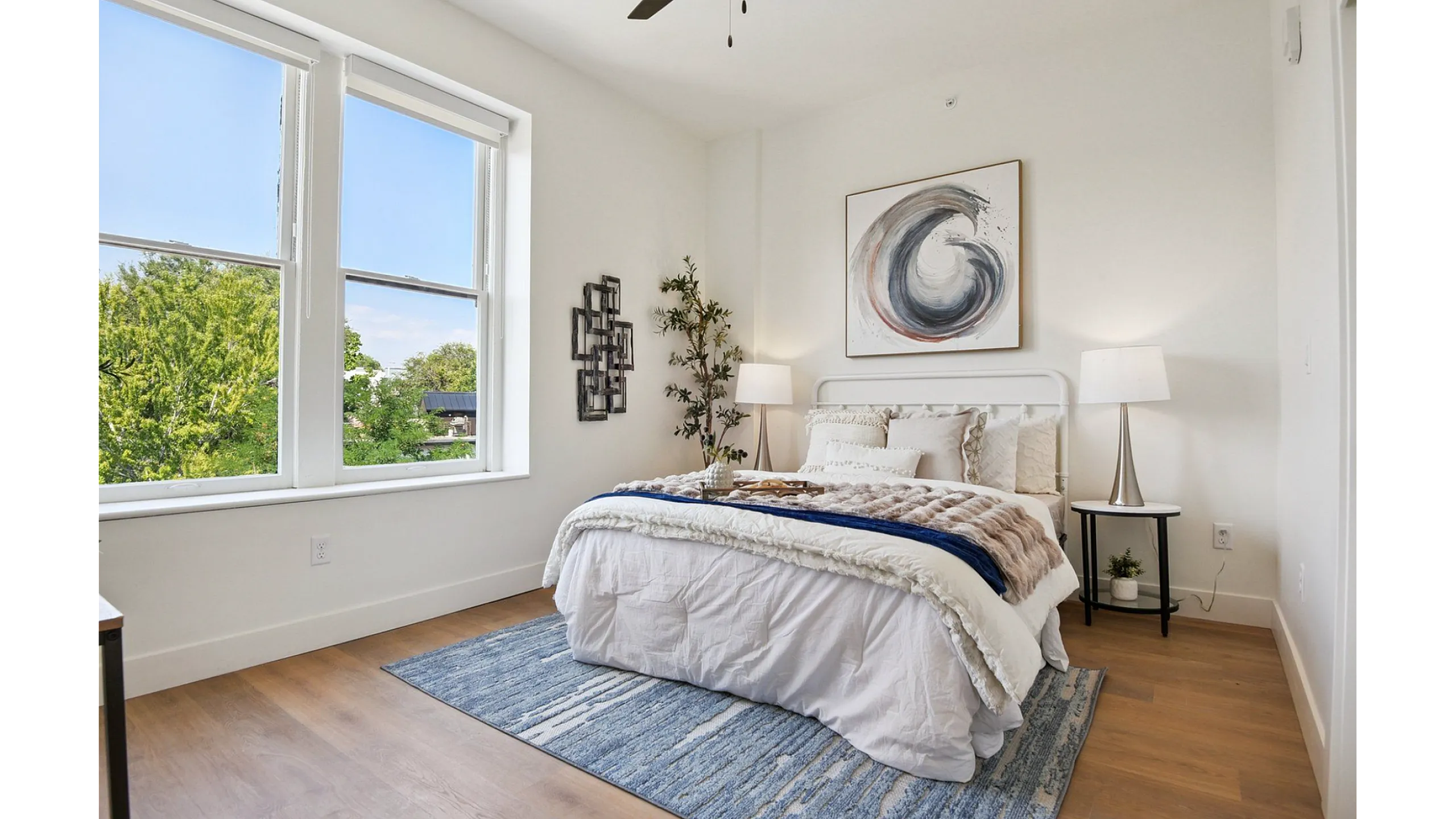 Elegant bedroom with a large window showcasing natural light, cozy bed with plush pillows, modern decor, and stylish lighting fixtures.