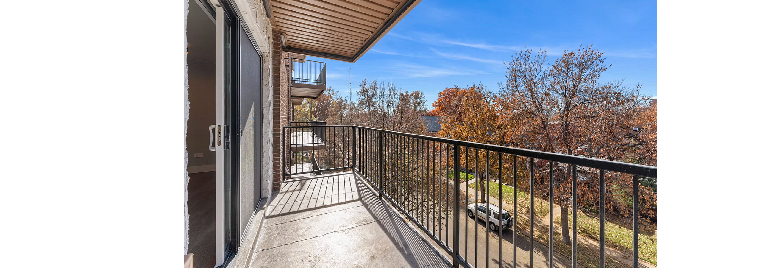 Inviting apartment balcony overlooking a scenic street, perfect for enjoying peaceful, tree-lined views.
