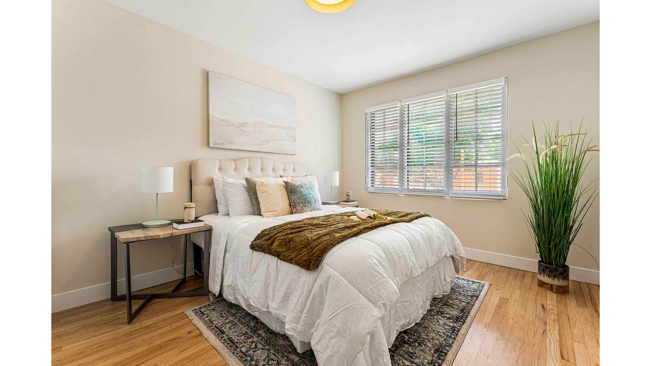 Inviting bedroom with plush bedding, elegant decor, and abundant natural light through large windows.