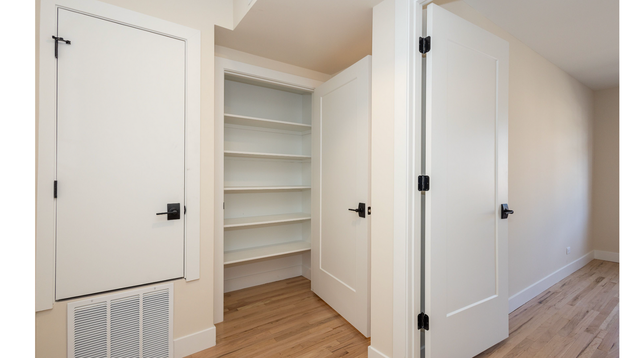 Modern apartment closet with white shelving and elegant hardwood floors, perfect for organized living.