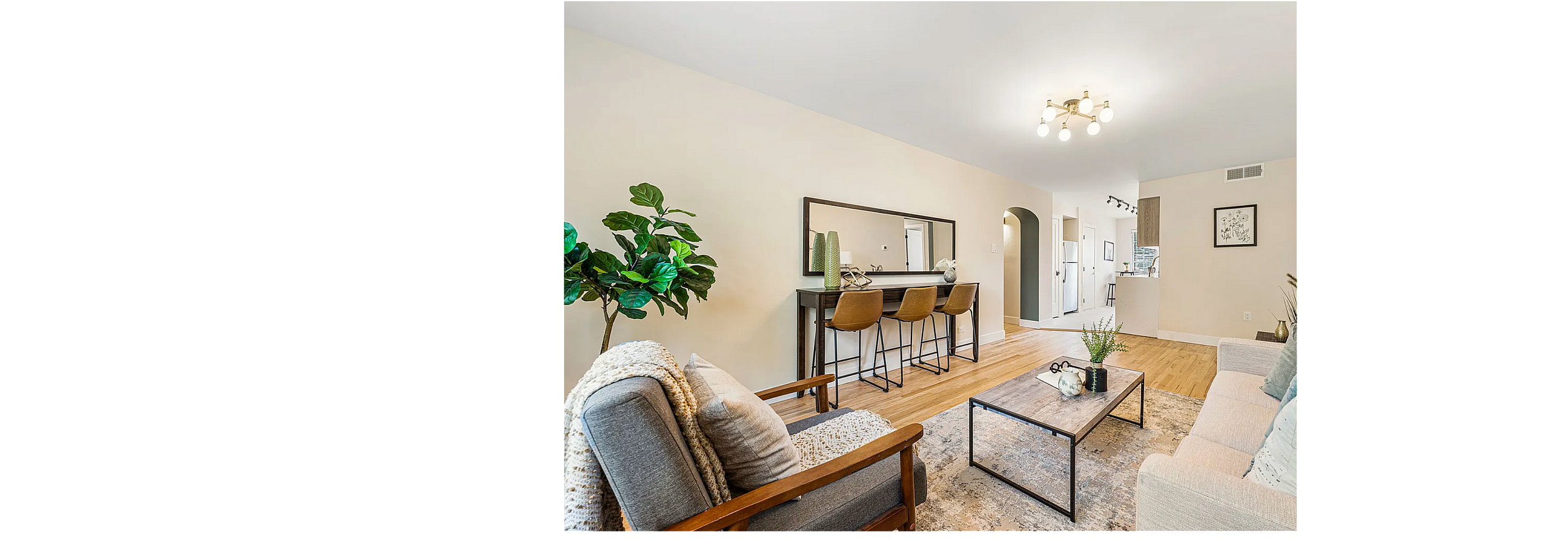 Modern living room with chic decor, bar seating, wooden floors, and natural light. Ideal for entertaining and relaxation.