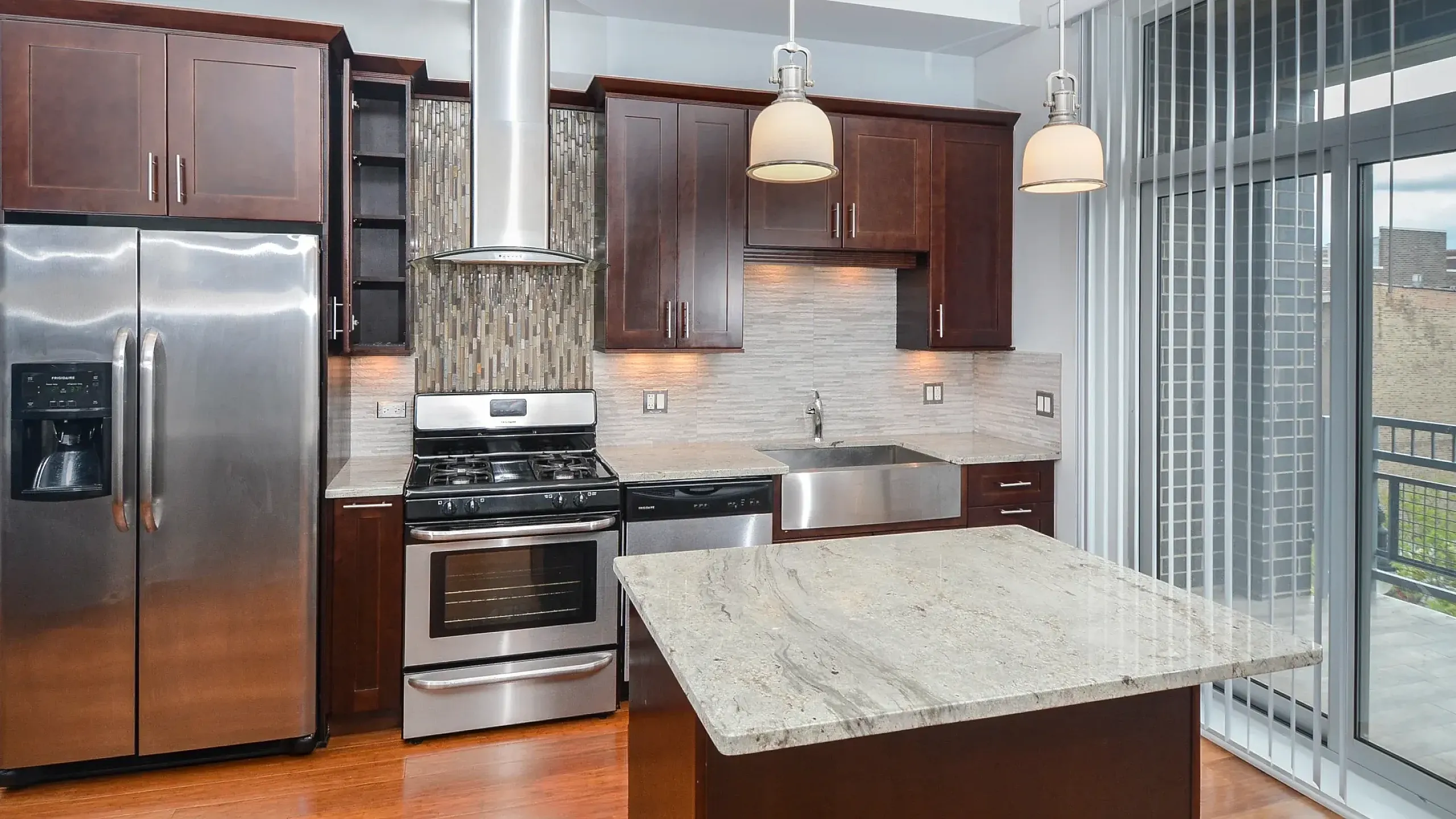 Modern kitchen with sleek stainless steel appliances, ample cabinetry, and elegant wood flooring, perfect for culinary enthusiasts.