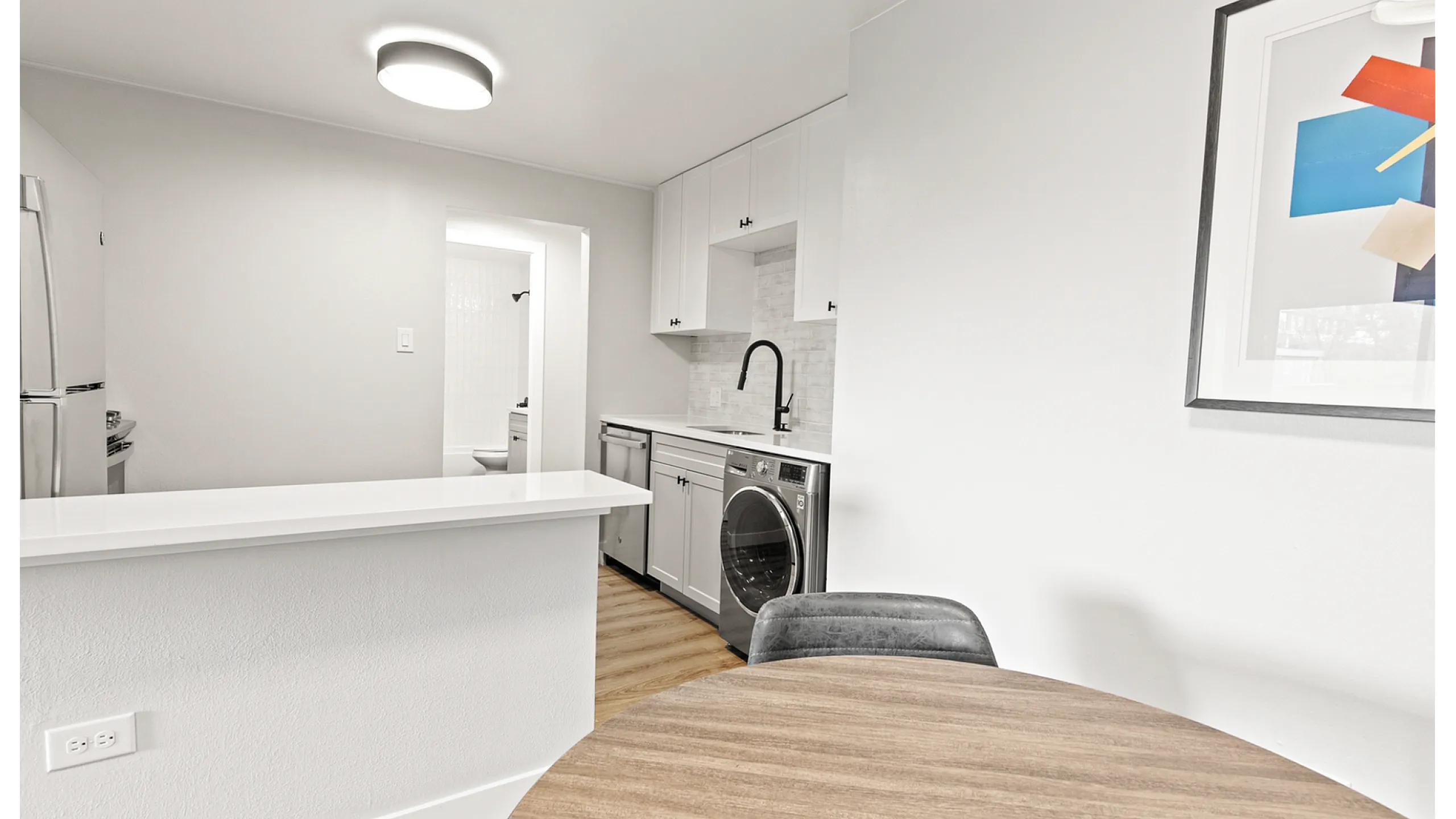 Modern kitchen with sleek stainless steel appliances, white cabinetry, and an inviting dining area.