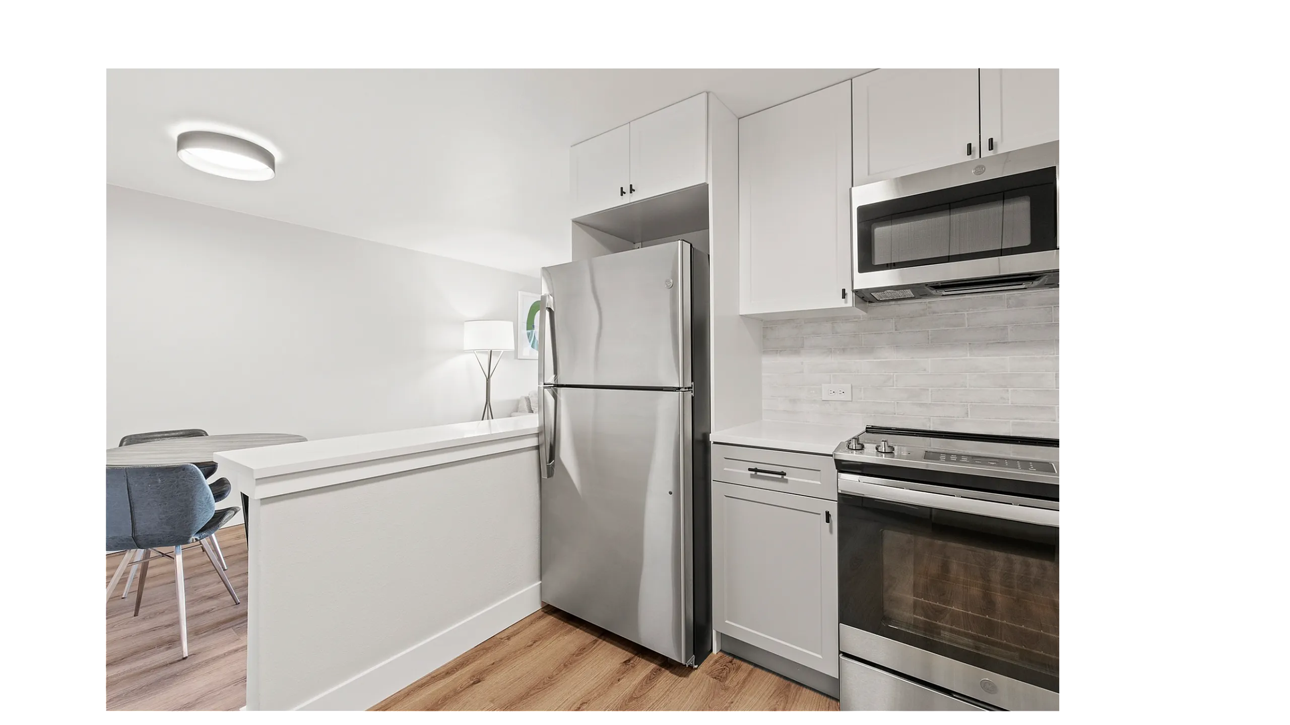 Modern kitchen with stainless steel appliances, chic cabinetry, and a bright dining area, highlighting elegant interior design.