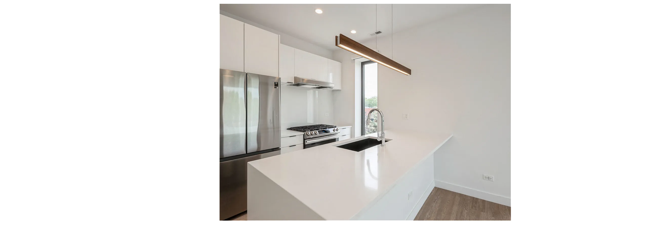 Sleek modern kitchen with stainless steel appliances, elegant white cabinetry, and a stylish island with a chic pendant light overhead.
