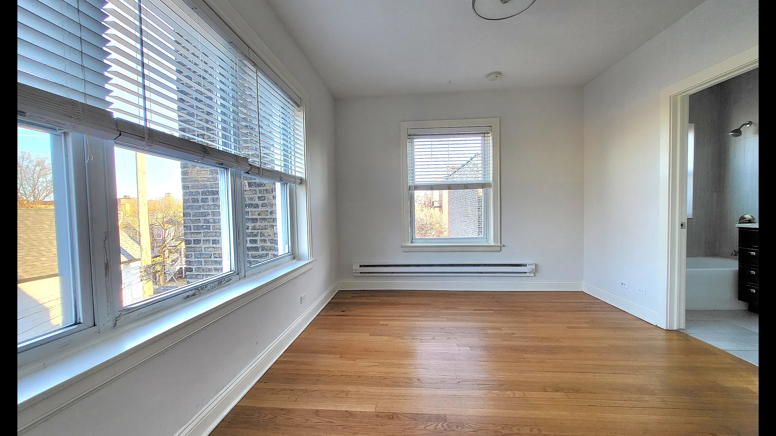 Bright, inviting room with large windows and warm wooden floors, perfect for a sunlit living space.