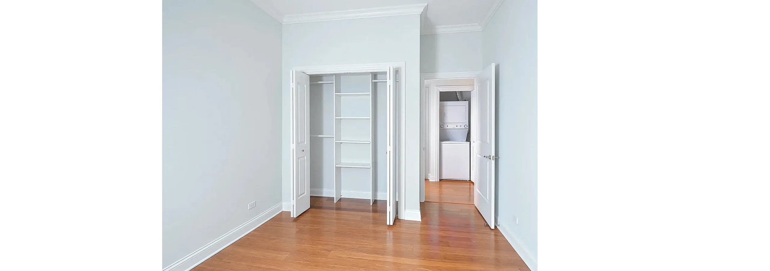 Bright room with open closet and hardwood floors, featuring a convenient in-unit washer and dryer for modern living.