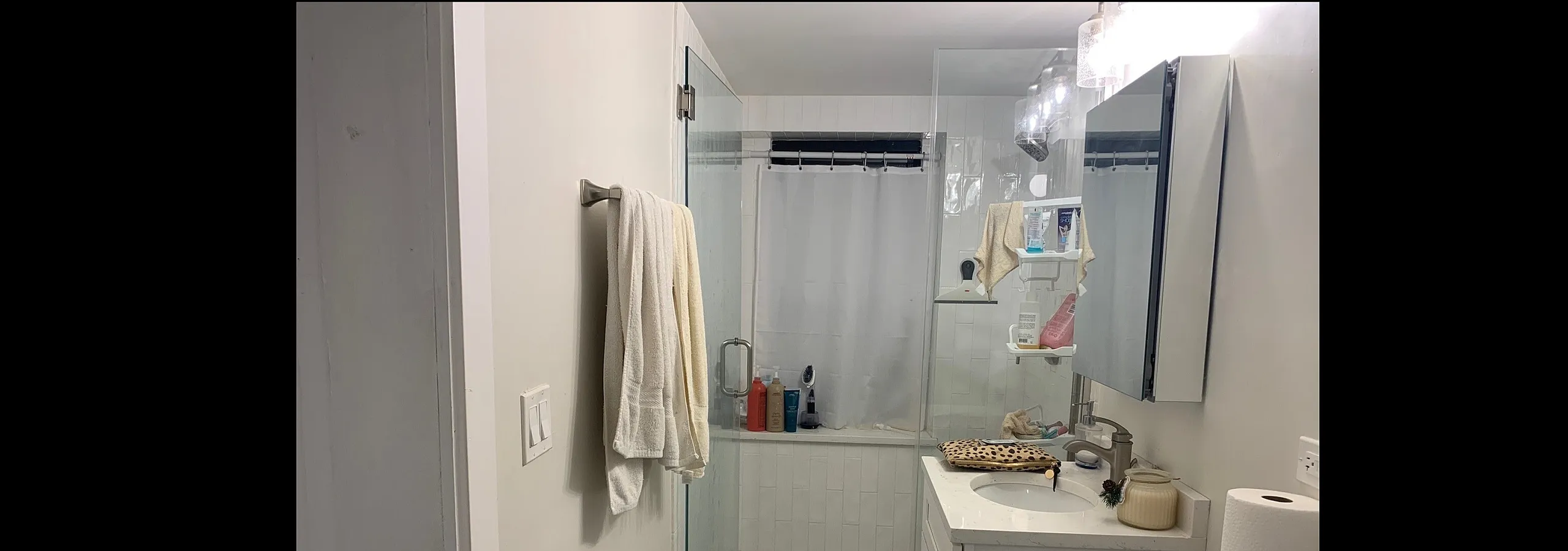 Modern bathroom featuring a sleek shower with glass doors, elegant vanity, and stylish lighting fixtures.