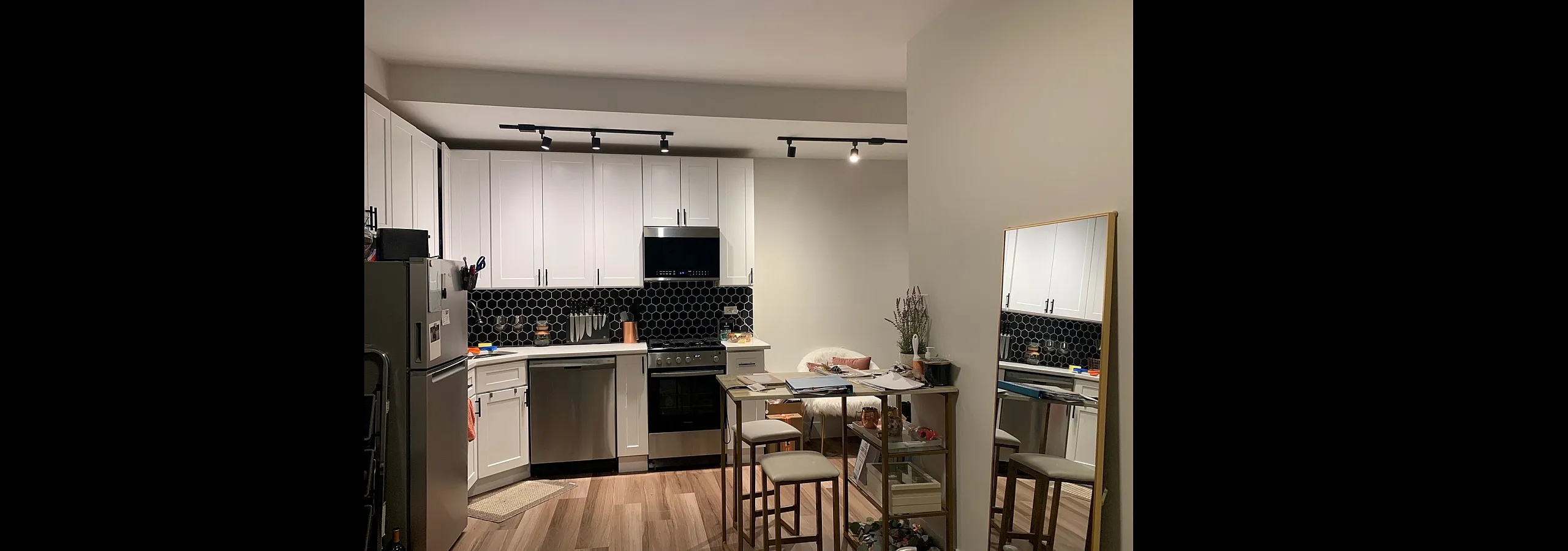Modern kitchen with sleek white cabinetry, elegant hexagonal black backsplash, and stylish stainless steel appliances, perfect for culinary enthusiasts.