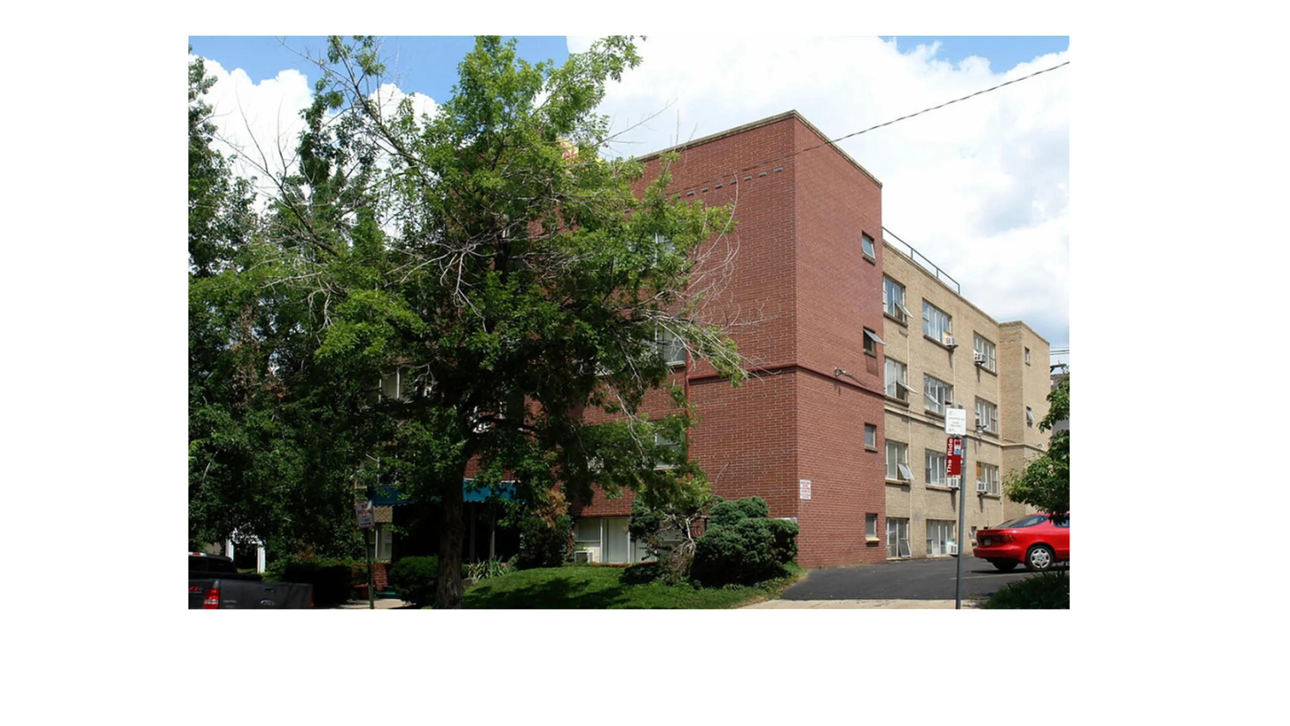 Charming brick apartment building with lush green surroundings, offering a serene and inviting living environment.