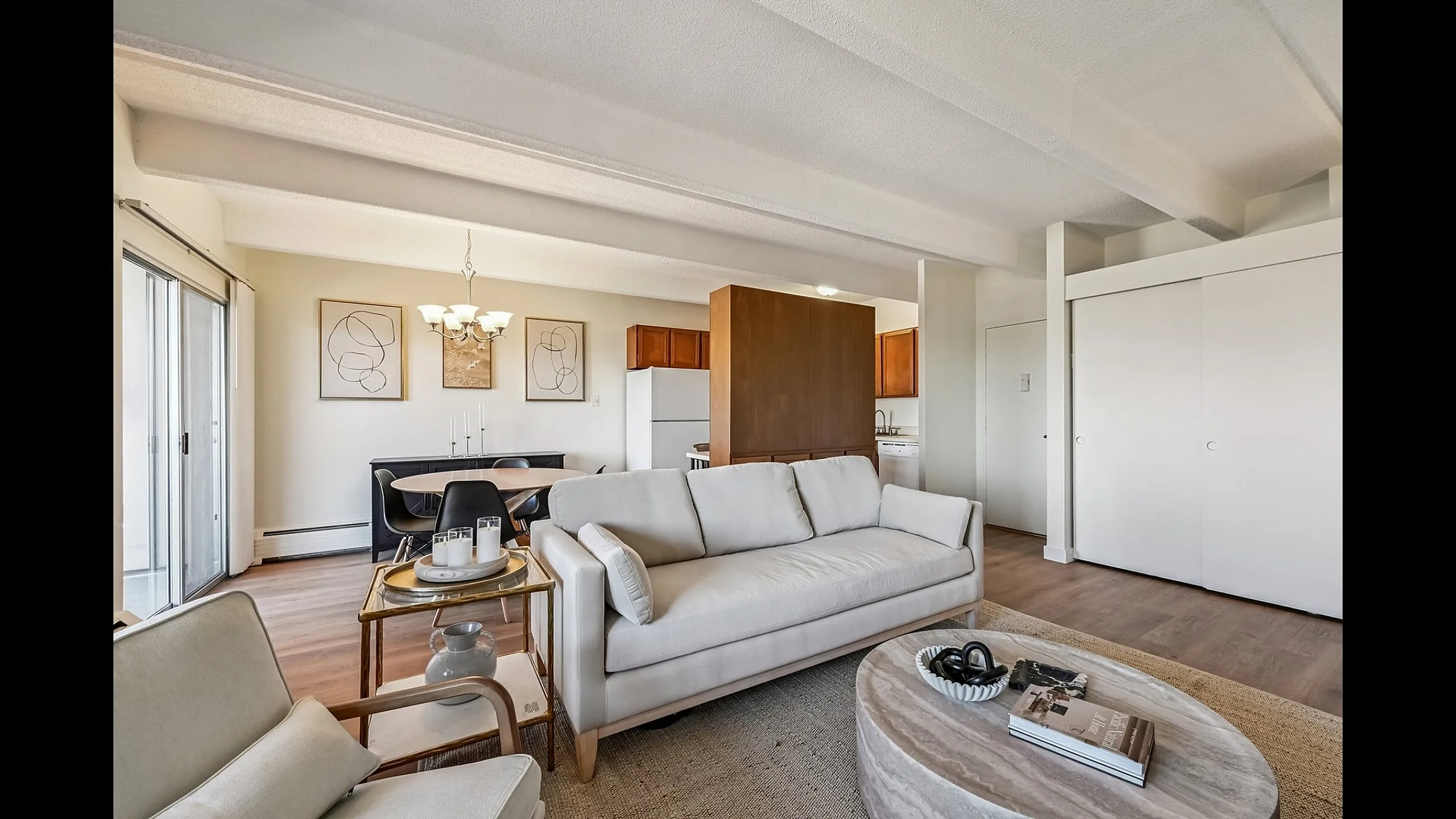 Bright and inviting living space with modern furniture, elegant decor, and an open-concept design leading to a cozy dining area and fully-equipped kitchen.