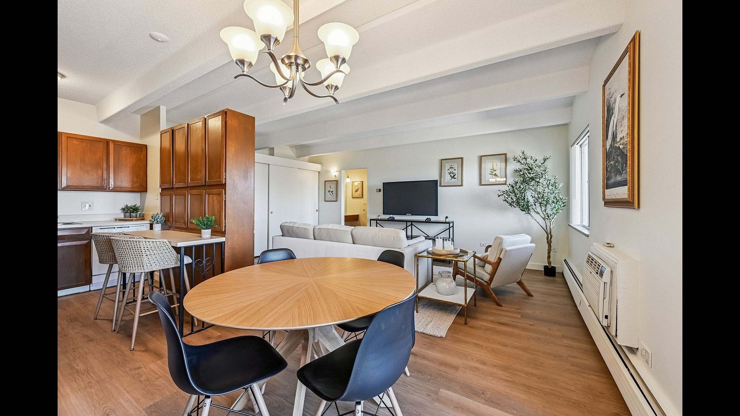 Inviting open-concept living area with stylish wooden furniture, modern kitchen, and cozy seating, perfect for entertaining.