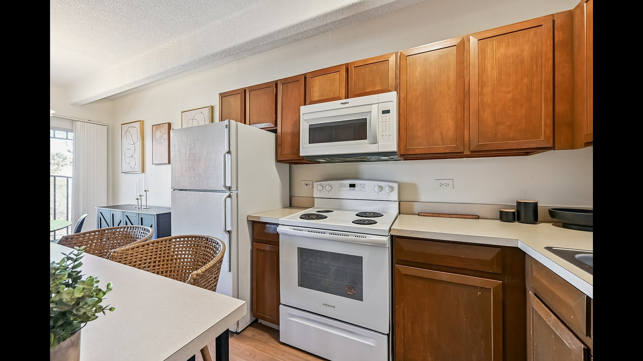 Bright and inviting kitchen featuring warm wooden cabinets, sleek appliances, and a cozy dining area with natural light.