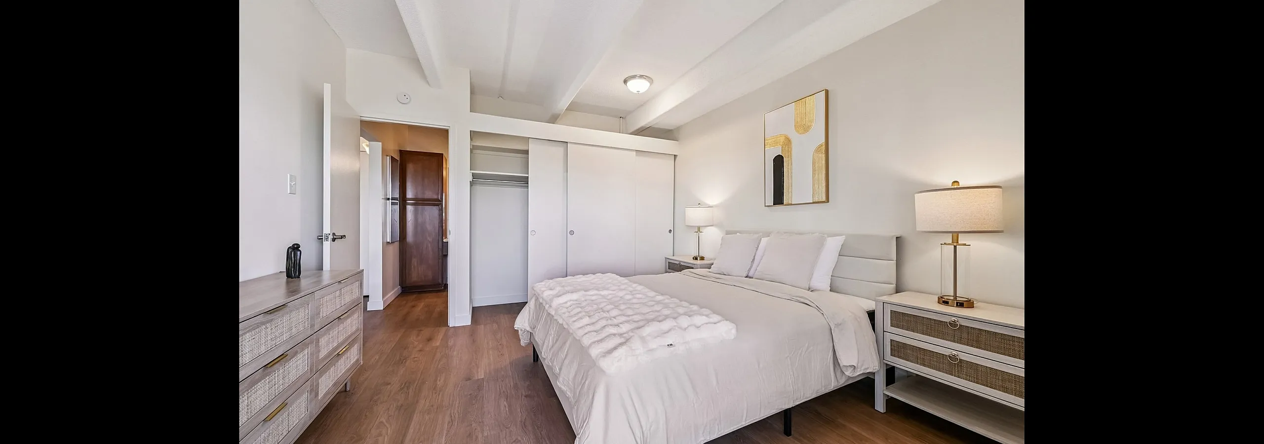 Elegant bedroom with modern decor, featuring a cozy double bed, stylish bedside tables, and ample closet space, enhanced by warm lighting and sleek wood flooring.
